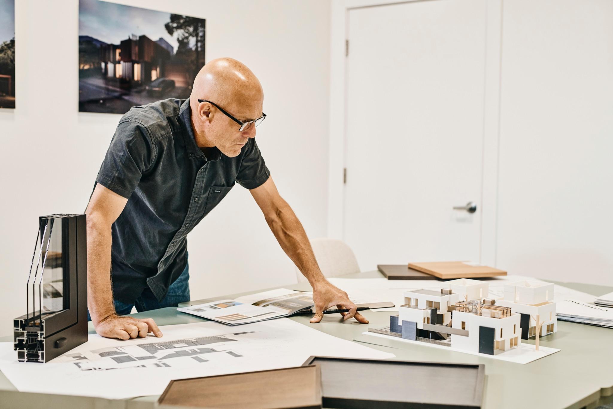 Wim de Jager studying material samples beside a model home on a worktable